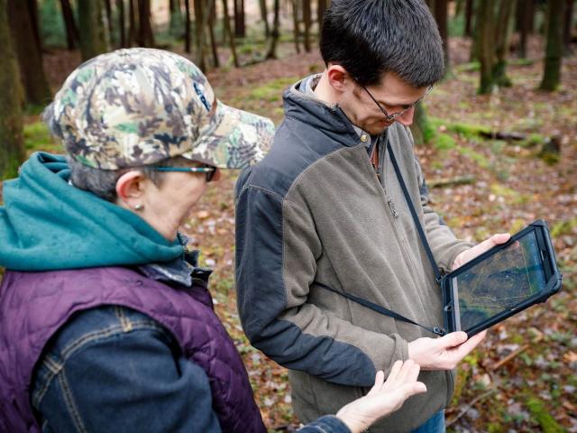 Two individuals viewing information on a tablet.